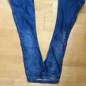 Blå jeans från Levi's - Säljer ett par klassiska blå jeans från Levi's med femficksdesign och knappgylf. Jeansen har en snygg tvätt och är perfekta för en avslappnad stil. De har en flare passform och är tillverkade i slitstarkt denim.