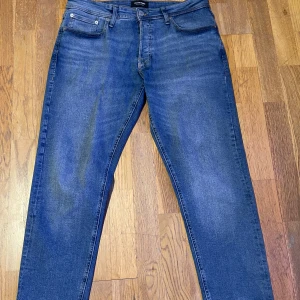 Jack & Jones Jeans - Blåa tapered fit jeans från Jack & Jones (Mike modellen), storlek 32/30. Mycket bra skick på dom, inga tecken på användning. Kontakta mig vid frågor!