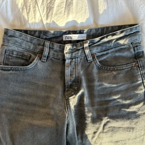 Grå jeansbyxor från Zara - Snygga grå jeansbyxor från Zara med klassisk femficksdesign. Byxorna har en rak passform och är perfekta för en avslappnad stil. De är tillverkade i ett slitstarkt material som ger en bekväm känsla hela dagen.