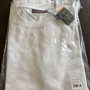 Vit t-shirt från Morris - Säljer en klassisk vit t-shirt från Morris i storlek M. T-shirten är kortärmad och tillverkad i mjuk bomull. Perfekt för en stilren och enkel look. Oanvänd pga fel storlek, fick i julklapp och var försent att skicka tillbaka.