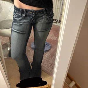 Blå bootcut jeans med broderi - Snygga blå lågmidjsde bootcut jeans med rosa broderi på bakfickorna. De har en ny påsydd knapp som funkar precis som vanligt och håller. Midjemåttet är ca 36 cm rakt över och innerbenslängden är ca 80 cm. De är däremot rätt stretchiga så midjan är runt 36-40 cm me tanke på stretchen💞💞