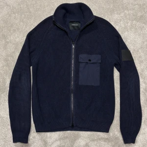 Stickad peak performance cardigan - Tja! Säljer denna riktigt snygga mörkblå stickade cardigan från peak performance! Cardiganen är i super fint skick, inga defekter! Size L passa även M, modellen på bilden är 182cm lång ish. Skriv vid funderingar!