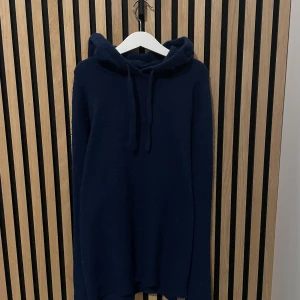 Merinoull tröja - Säljer en mysig mörkblå merinoull hoodie med långa ärmar och justerbar huva. Perfekt för kyliga dagar och avslappnade stunder. Enkel och stilren design som passar till det mesta. Tröjan är något nopprig men borde gå och få bort🤩