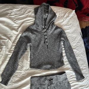 Grå hoodie från Stronger - Säljer ett sett från stronger.  snygg grå hoodie och matchande leggings i storlek medium. Den är stickad och har en croppad passform med långa ärmar och snörning i huvan. Perfekt för en avslappnad stil. Nypris 1299kr