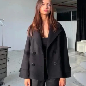 Svart kappa med knappar design by Si - Snygg svart kappa med dubbelknäppning och bred krage. Jackan har långa ärmar och en stilren design som passar perfekt för kyligare dagar. Perfekt för en trendig look!