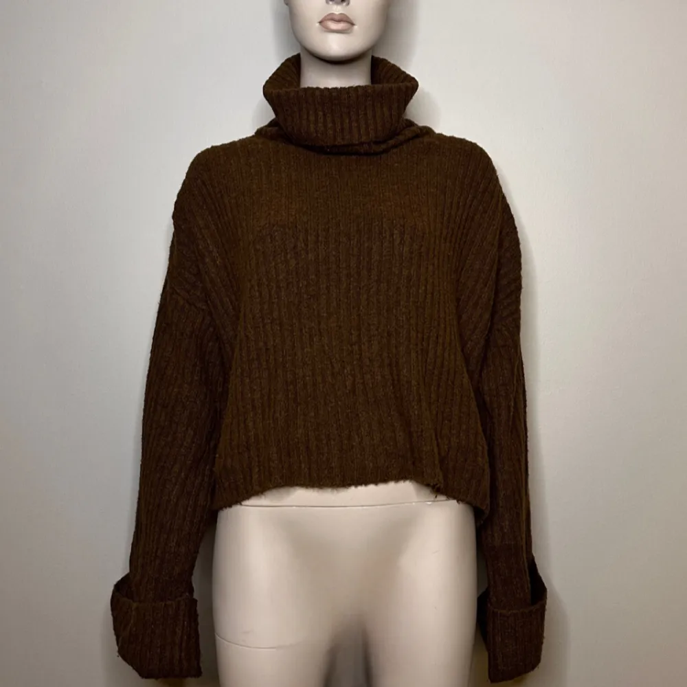 Brun stickad polotröja från Gina Tricot. Tröjan har en croppad design med långa ärmar och en hög polokrage. . Neuleet.