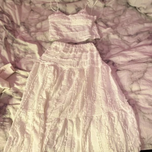 Kjol/ topp - Vit topp och kjol storlek No size men skulle säga att toppen passar storlek xs/s, och kjolen xs,s,m då den är stretchig. Helt ny bara testad, köpt för ca 300kr säljer för 100kr pris kan diskuteras. Kjolen är lång och har en volangdetalj, perfekt för sommaren! 