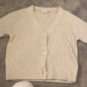 Kofta  - Säljer en beige ribbad kofta från Kappahl i storlek XS. Koftan har en v-ringad design med knappar framtill. Använd några gången men är o bra skick 