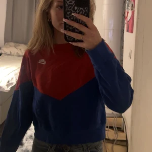 Röd och blå tröja från Nike - Säljer en cool röd och blå tröja från Nike. Tröjan har en sportig look med långärmade ärmar och en klassisk Nike-logga på bröstet. Perfekt för en avslappnad stil. Storlek L men sitter som en oversized (är normalt S) den är använd