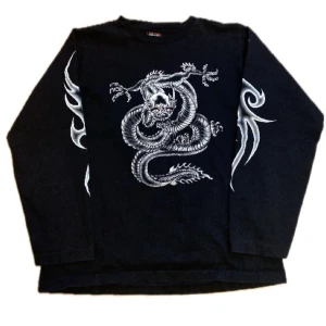 Drainer long sleeve - Cool svart långärmad tröja med ett detaljerat drakmotiv i silver på framsidan och tribaldesign på ärmarna. Perfekt för dig som vill ha en unik stil. 