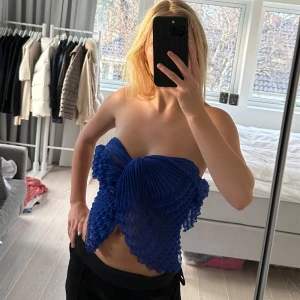 Blå axelbandslös topp sjal - Säljer en unik blå axelbandslös topp med ett iögonfallande veckat mönster. Toppen har en elegant struktur och är perfekt för att sticka ut. Det är en sjal egentligen som man enkelt kan knyta till en så fin topp! Märket på sjalen är Kriss Sweden, nypris är 299kr.