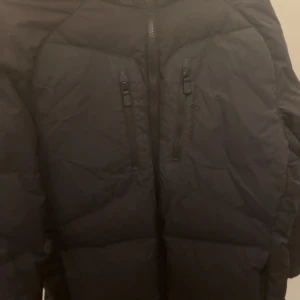 Sail racing jacka black logo - Säljer en svart dunjacka från Sail Racing i storlek medium. Jackan har en stilren design med dragkedja framtill och två praktiska bröstfickor med dragkedjor. Jacka har svart sail racing märke . Säljer den då den har blivit för liten . Kan fraktas men även mötas upp i Stockholm.