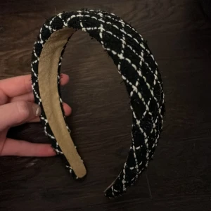 Stockholm stil diadem - Snyggt diadem i svart och vitt med ett klassiskt rutigt mönster. Perfekt för att ge en stilfull touch till din outfit. Diademet har en vadderad design för extra komfort.