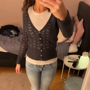 Grå shimrig kofta - Säljer en snygg grå kofta med knappar framtill. Koftan har ett fint hålmönster och långa ärmar samt lite shimer😻