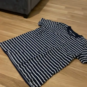 Randig t-shirt från Lee - Säljer en snygg randig t-shirt från Lee i marinblått och vitt. T-shirten har en klassisk design med korta ärmar och rund hals. Perfekt för en avslappnad stil.