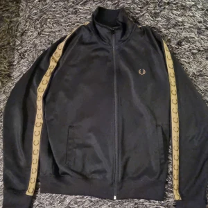 Fred perry tracksuit  - Fin fred perry tracksuit i svart och gult den e i bra skick och I storlek L ganska normal I storleken men den funkar även för mig som har M Original priset var ungefär 1500 