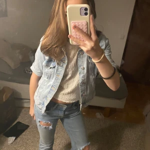 Ljusblå jeansjacka - Säljer en snygg ljusblå jeansjacka med knappar framtill. Jackan har en croppad passform och är perfekt för vår och sommar. Den har långa ärmar och klassisk krage. Perfekt för en avslappnad look!