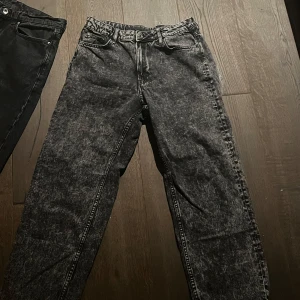 Grå aktiga jeans - Två par jeans i svart och grått. De svarta jeansen har en klassisk design med fem fickor och knappgylf. De grå jeansen har en tvättad look med en något lösare passform. Båda paren är perfekta för en avslappnad stil. Behöver få bort snabbt!!!!!