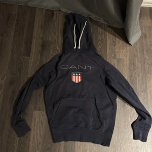 Mörkblå hoodie från Gant priset är förhandlingsbart - Säljer en snygg mörkblå hoodie från Gant. Tröjan har en stor ficka framtill och justerbar huva med vita snören. Perfekt för en avslappnad stil. 