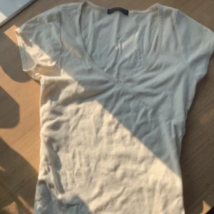 Beige v-ringad topp - Säljer en stilren beige v-ringad topp med korta ärmar. Perfekt för en enkel och snygg look. Toppen är i ett mjukt material som sitter bekvämt på kroppen.