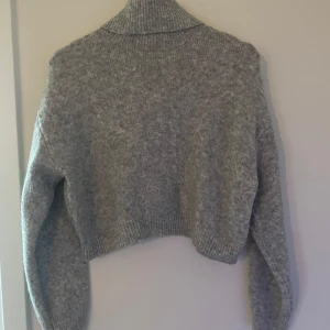 Grå stickad polotröja  - En grå mysig croppad polotröja i med ribbat nertill. Storlek Xs men sitter bra på de med S också, använd någon enstaka gång så fortfarande i väldigt bra skick.