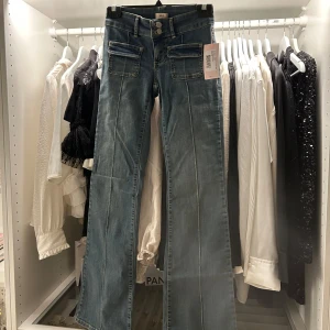 Blå bootcut jeans från Nelly - Snygga vintageblå low waist bootcut jeans från Nelly med dubbla knappar och framfickor. Perfekta för en avslappnad stil med en touch av retro. Jeansen är helt oanvända och lappen sitter kvar! Om du har några frågor eller funderingar så ska du inte tveka på att kontakta⭐️