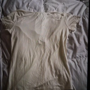 Vit topp med knytband från 157 - Säljer en vit topp från 157 med korta ärmar och knytband i ryggen. Perfekt för en stilren look. Toppen har en rund halsringning och är tillverkad i ett mjukt material.