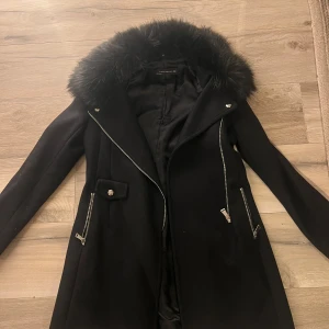 Svart kappa från Zara - Snygg svart kappa från Zara Woman med pälsdetaljer på kragen. Så fin och endast använd 1 gång!