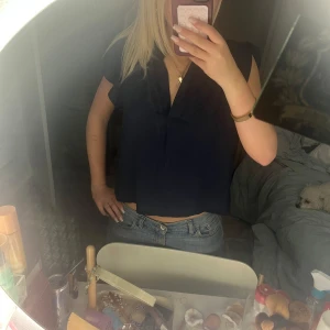 Mörkblå blus - Säljer en stilren mörkblå blus med v-ringning. Blusen har korta ärmar och en lös passform, perfekt för en avslappnad look. Passar bra till jeans eller kjol. Aldrig använd därför säljs. Köpt från Lindex för 1 år sen.💘