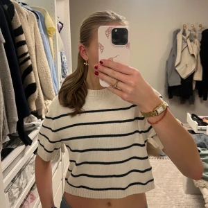 Stickad & randig topp från H&M - Säljer en söt vit stickad  tröja från H&M med svarta ränder. Tröjan är lite croppad och har korta ärmar, perfekt för en stilren look. Den har ett mjukt material. Den är i fint skick🦓💞original pris:279kr