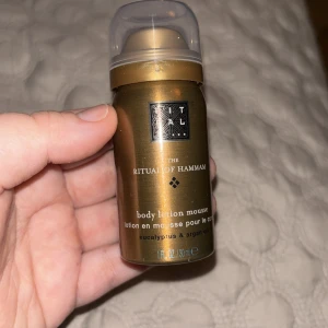 Body lotion mousse från The Ritual of Hammam - Säljer en lyxig body lotion mousse från The Ritual of Hammam. Den kommer i en elegant guldbrun flaska med en praktisk pump. Innehåller eukalyptus och arganolja för en uppfriskande och återfuktande upplevelse. Perfekt för att skämma bort huden med en spa-liknande känsla hemma.
