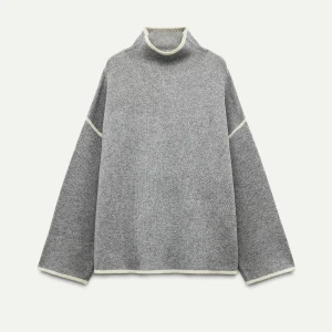 Grå stickad tröja med hög krage - Säljer en stilren grå stickad tröja med hög krage och långa ärmar. Tröjan har vita detaljer vid ärmslut och nederkant som ger en snygg kontrast. Perfekt för kyligare dagar. Slutsåld hos Zara!