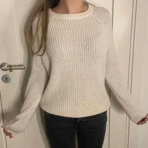 Vit stickad tröja - Säljer en stilren vit stickad tröja med rund hals och långa ärmar. Perfekt för kyligare dagar och enkel att matcha med olika outfits. Tröjan har en mjuk och bekväm passform. Storlek L men är väldigt liten i storleken och passar mer S