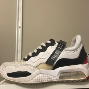 Nike Air Jordans med svart och röd detalj - Snygga Nike Air Jordans med en kombination av vita, svarta och röda detaljer. Skorna har en synlig Air-enhet i sulan och klassisk snörning. Perfekta för dig som vill ha en stilren och sportig look.