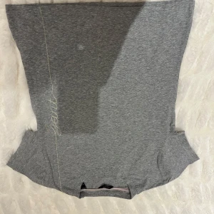 Grå t-shirt från GANT - Säljer en stilren grå t-shirt från GANT med korta ärmar och ett subtilt broderat märke i vitt på framsidan. Perfekt för en avslappnad look.