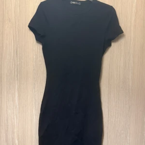 Svart kortklänning från Zara - Snygg svart kortklänning  i en enkel och stilren design. Klänningen har korta ärmar och en tight passform som framhäver figuren. Perfekt för en minimalistisk look. Aldrig använd