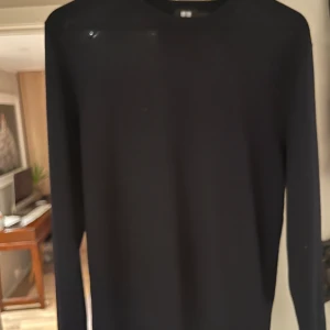 Svart tröja från Uniqlo - Säljer en stilren svart tröja från Uniqlo. Tröjan har en klassisk design med rund hals och långa ärmar, perfekt för en minimalistisk look. Passar bra till både vardag och mer uppklädda tillfällen.
