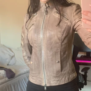 Brun skinnjacka med dragkedjor - Snygg brun/beige skinnjacka med flera dragkedjor, knappar och detaljer. Köpt vintage men i jättebra skick