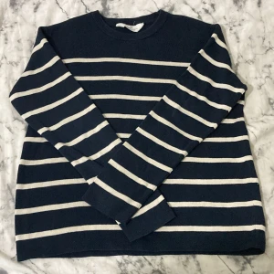 Stickad tröja från H&M i marinblått och vitt - Säljer en stilren randig tröja i marinblått och vitt. Tröjan har långa ärmar och en klassisk rund halsringning. Perfekt för en avslappnad look. Pris går att diskutera