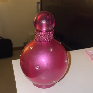 Tom Parfymflaska Britney Spears Fantasy - Säljer en rosa tom parfymflaska från Britney Spears. Flaskan är rund och rymmer 100 ml. OBS: Tom!