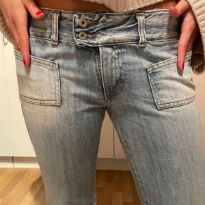 Ljusblå jeans med bootcut - Snygga ljusblå jeans med bootcut-stil och låg midja. De har dubbla knappar i midjan och framfickor. Älskar dessa jeans! Mått på jeansen, midjan rakt över 40cm, jag är 170.