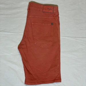 Pepe Jeans shorts - Snygga rostfärgade shorts från Pepe Jeans med klassisk femficksdesign. Tillverkade i bomull med en liten del elastan för extra komfort. Perfekta för en avslappnad stil. Storleken är W30, L30 och de är slim fit. Använda många gånger så de är tvättade många gånger. 