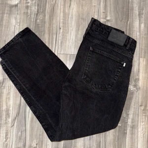 Svarta jeans från Woodbird - Snygga svarta jeans från Woodbird i en klassisk straight fit. Perfekta för en stilren look. jag väljer att sälja dessa jeans för jag har märkt att jag inte haft användning till dem jag haft på mig dem fyra fem gånger och tvättat dem tre gånger. Jeansen har inga defekter förutom att de har förlorat lite färg Men det är ingenting man märker av bara om man kollar noggrant. jag är 185 cm lång och dessa jeans är bara för små och inte min stil. Pris går att diskuteras vill bara få de sålda