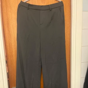 Oanvända kostymbyxor från object  - Snygga mörkgrå kostymbyxor från Object i storlek 38. Byxorna har en elastisk midja baktill för extra komfort och stilrena fickor. Helt oanvända med prislapp kvar. Vida ben skriv för bättre bilder!