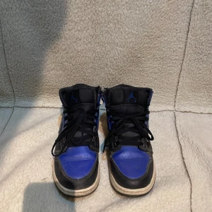 Nike Air Jordans i svart och blått - Säljer ett par klassiska Nike Air Jordans i svart och blått. Skorna har en hög modell med snörning och en ikonisk design. Pris kan diskuteras.