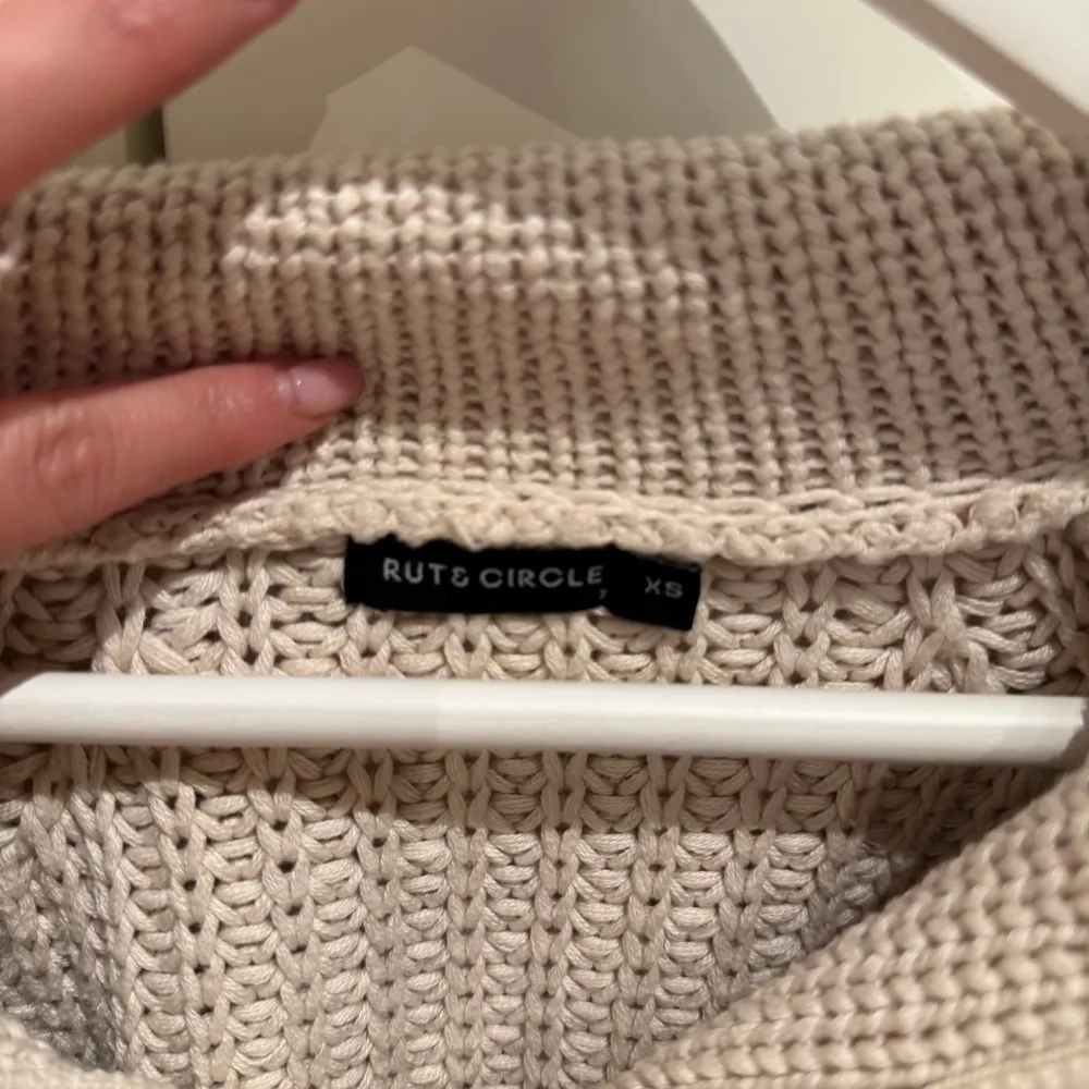 Mysig beige stickad tröja från Rut & Circle med dragkedja vid halsen. En stilren och bekväm tröja för alla tillfällen❄️❤️. Neuletakit & Villapaidat.