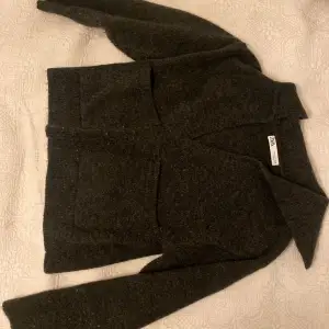 Säljer en mysig mörkgrå stickad tröja från Zara. Tröjan har en v-ringad design och långa ärmar, perfekt för kyligare dagar. Den är både stilren och bekväm, vilket gör den till ett mångsidigt tillskott i garderoben.