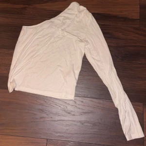 Beige oneshoulder topp från Gina Tricot - Säljer en stilren vit oneshoulder topp från Gina Tricot. Mjuk material och alldeles oanvänd. Pris går o diskutera🤍