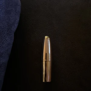Guldigt läppstift - Elegant läppstift i en lyxig guldig hylsa. Färgen är en mjuk nude-ton, perfekt för en naturlig look. Den smidiga förpackningen gör det enkelt att ta med i väskan.
