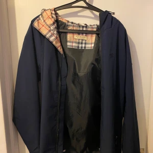 Mörkblå jacka från Burberry - Riktigt fet burburrry vind/regnjacka som inte har hål eller så, däremot lite lim vid handleden som man ser. Priset går att diskutera. Sitter mer som S